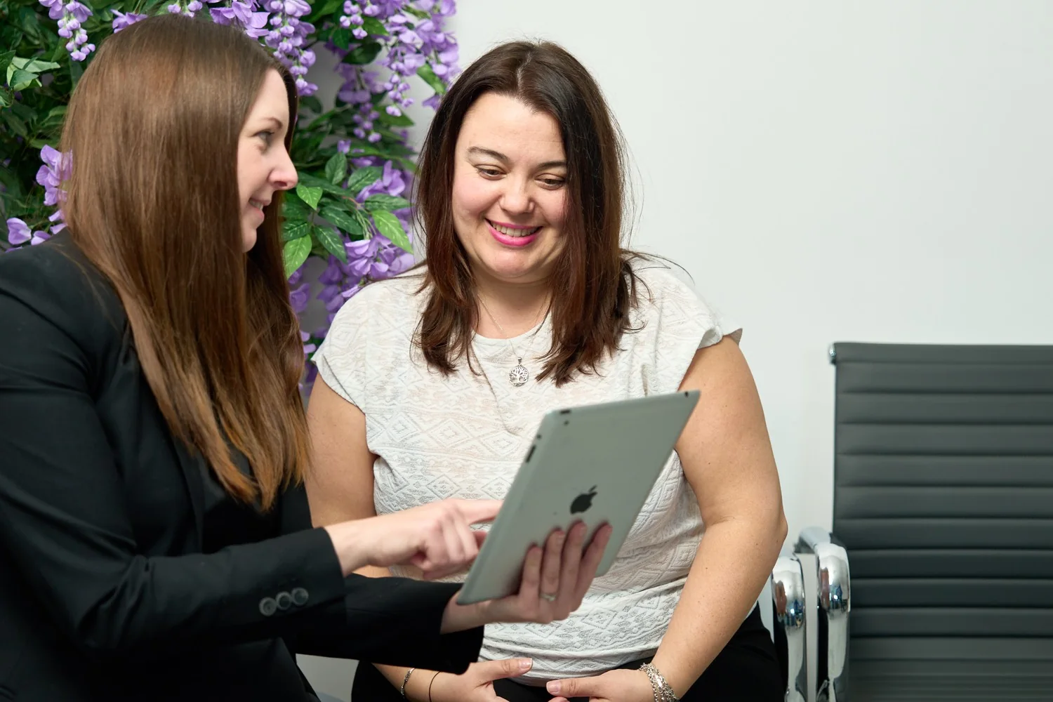 A patient care coordinator going through recovery information on a tablet with a smiling patient