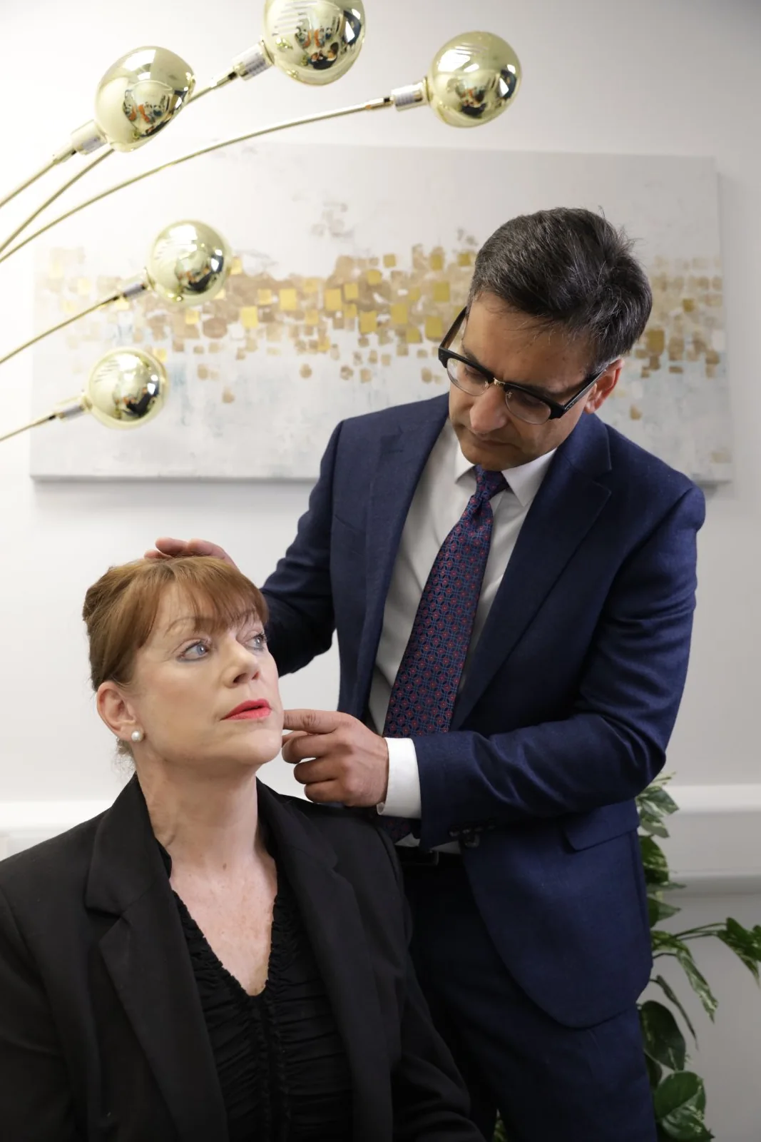 Mr Supriya assessing a patient's jawline during a consultation